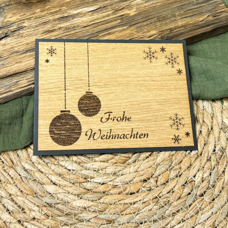 Holz-Weihnachtskarte "Frohe Weihnachten & Christbaumkugeln" Unterhalb des feinen Schneeflockenmotivs steht in geschwungener, eleganter Schrift der klassische Weihnachtsgruß „Frohe Weihnachten“. Diese Karte kombiniert traditionelle Festlichkeit mit moderner Nachhaltigkeit und ist eine wunderbare Alternative zu herkömmlichen Papierkarten. Jede Karte wird aus hochwertigem Holz gefertigt und kann als Dekoration unter Weihnachtsbaum oder im Haus einen Ehrenplatz finden, sodass der festliche Gruß weit über die Feiertage hinaus Freude bereitet. Diese Holz-Weihnachtskarte ist nicht nur ein Gruß, sondern auch ein kleines Geschenk und eine schöne Erinnerung an die gemeinsame Zeit. Ideal für alle, die in dieser Saison Umweltbewusstsein und festlichen Geist in Einklang bringen möchten. Die Holzkarte klebt auf einem schwarzen Kraftpapier-Billett. Innen befindet sich weißes Papier, damit du auch noch deine persönlichen Worte darauf schreiben kannst. Dir gefallen unsere Holz-Weihnachtskarten? Dann sieh dir doch auch unsere anderen Glückwunschkarten an.